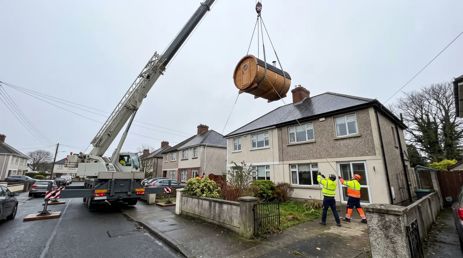 Crane lifting a barrel sauna over a house with no side access